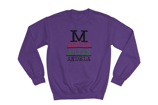 Purple crewneck sweatshirt with the text 'MALCOLM MARTIN MANDELA' stacked vertically on the chest. The 'M' in Malcolm, Martin, and Mandela is large and black. 'ALCOLM' is in red, 'ARTIN' is in green, and 'ANDELA' is in black.